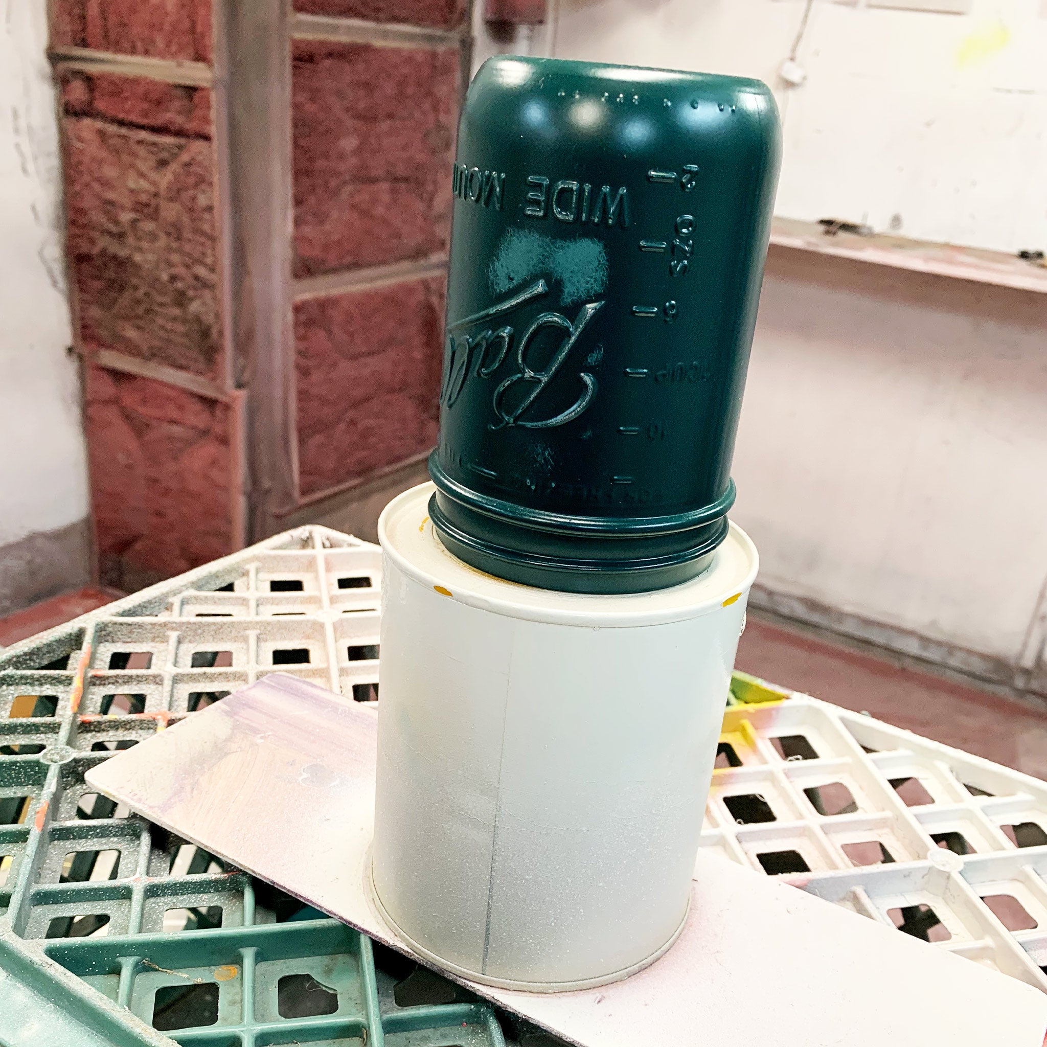 Green mason jar on a white stand in a workshop.
