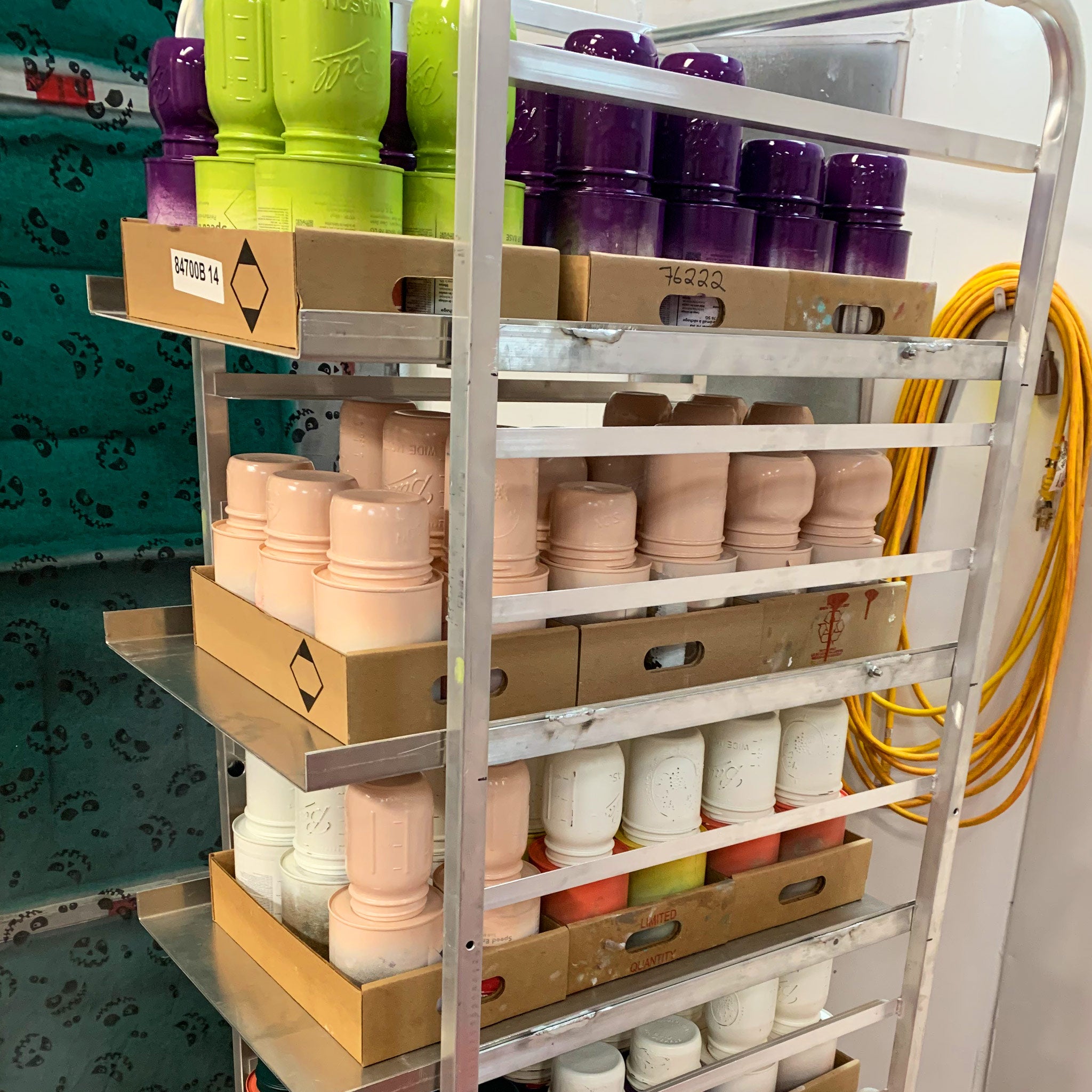 Shelving unit with drying mason jars painted in various colours.
