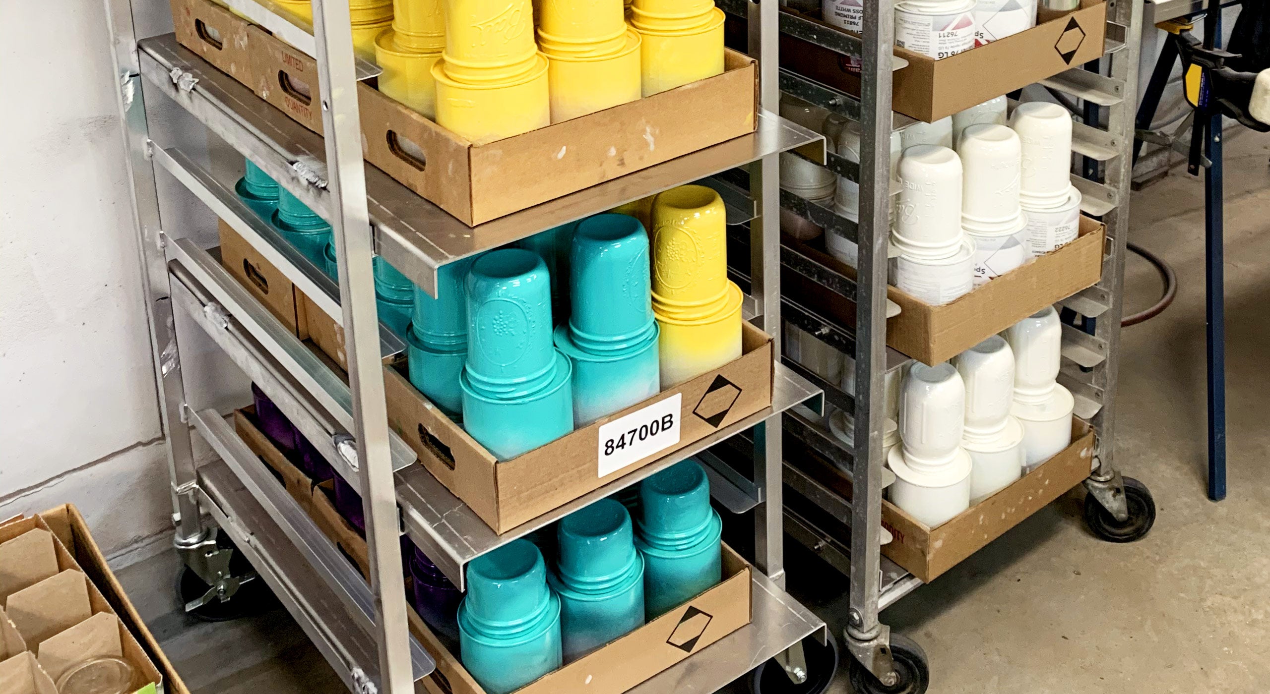 A metal rack with yellow and teal painted mason jars drying on them.