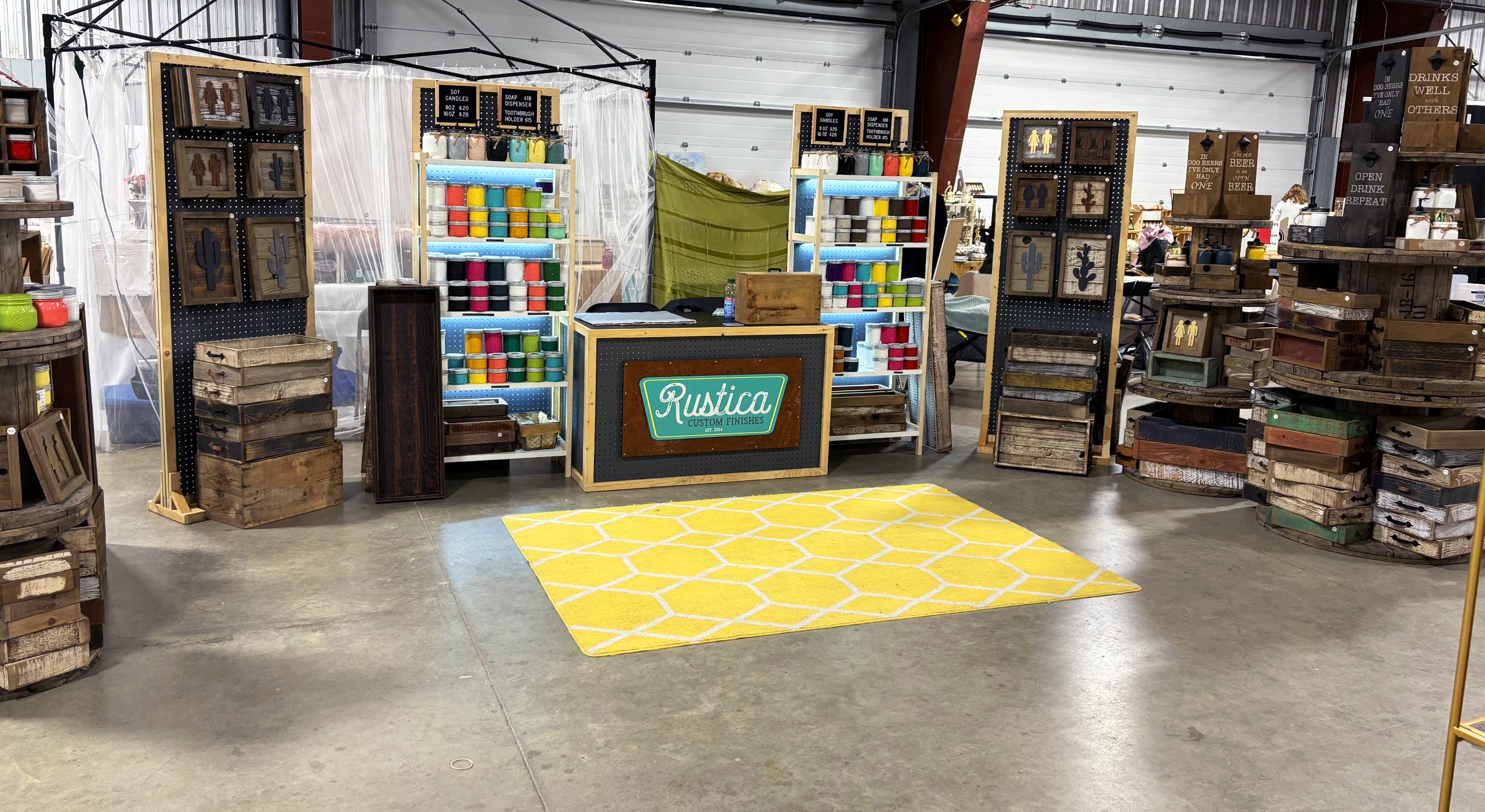 Rustica's market display with colourful mason jar candles and wooden home decor and a yellow rug with a pattern.