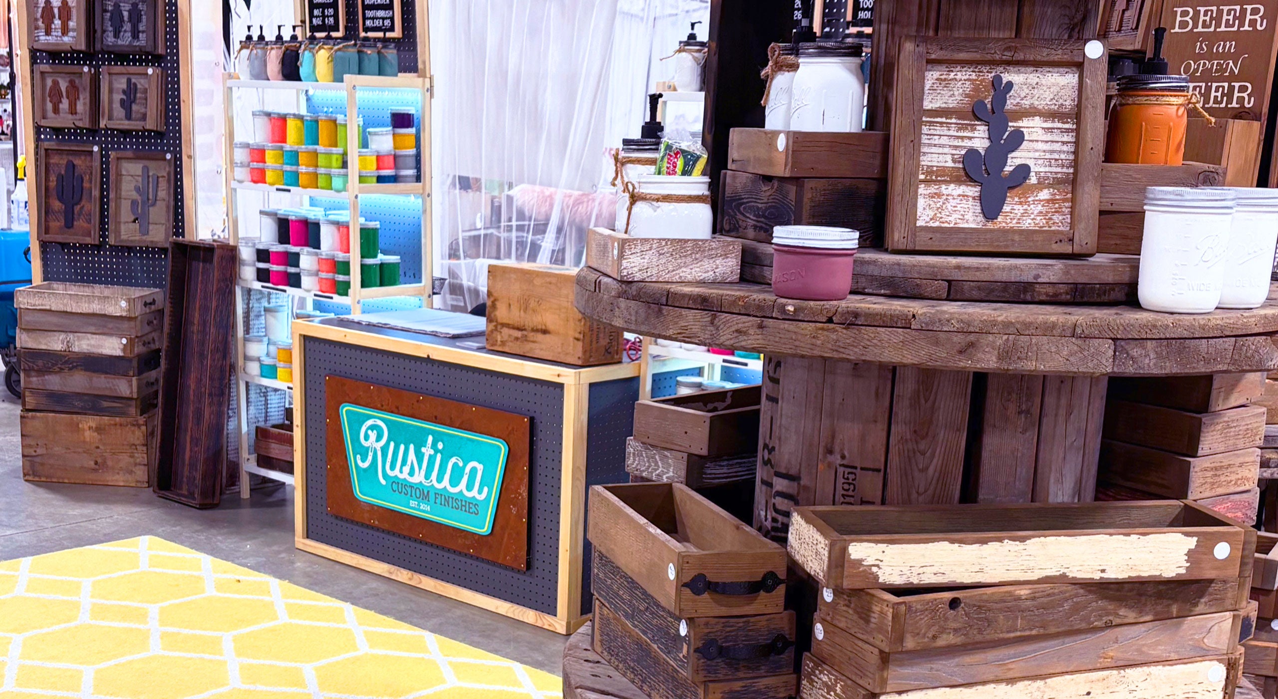 Display of wooden products and decor items with 'Rustica' branding in a market setting.