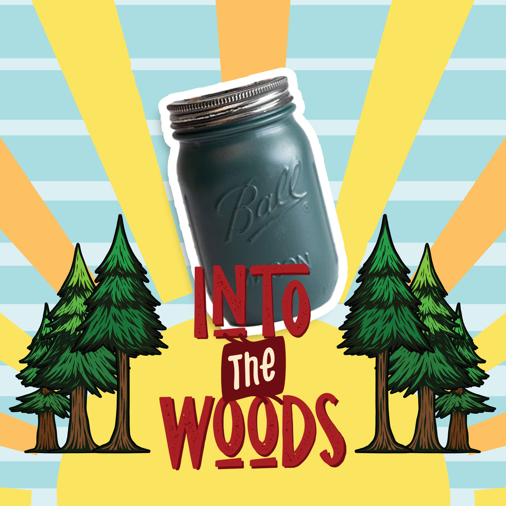 A dark green mason jar candle on a colorful background with trees and 'Into The Woods' text.