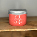 Coral mason jar with silver lid on a wooden surface.