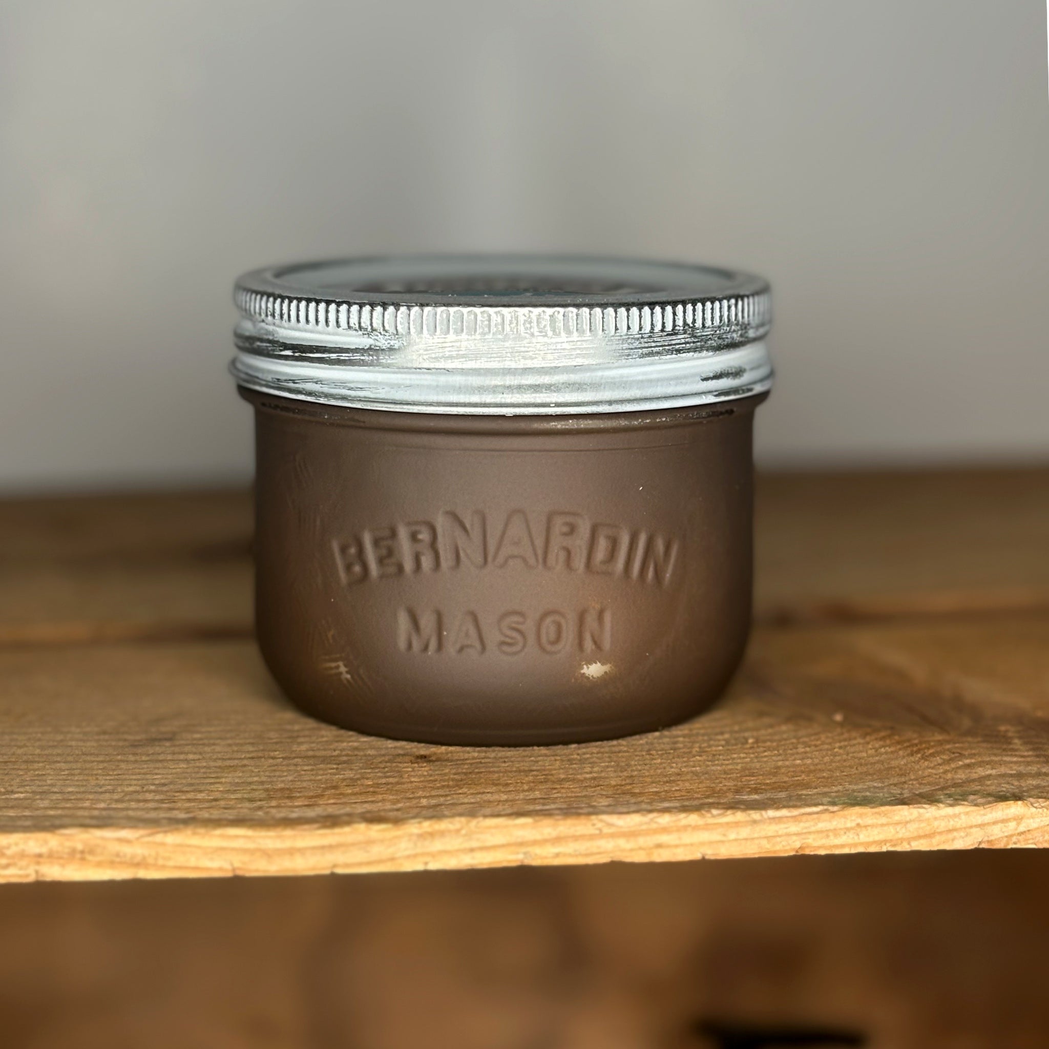 Brown mason jar with silver lid on a wooden surface.