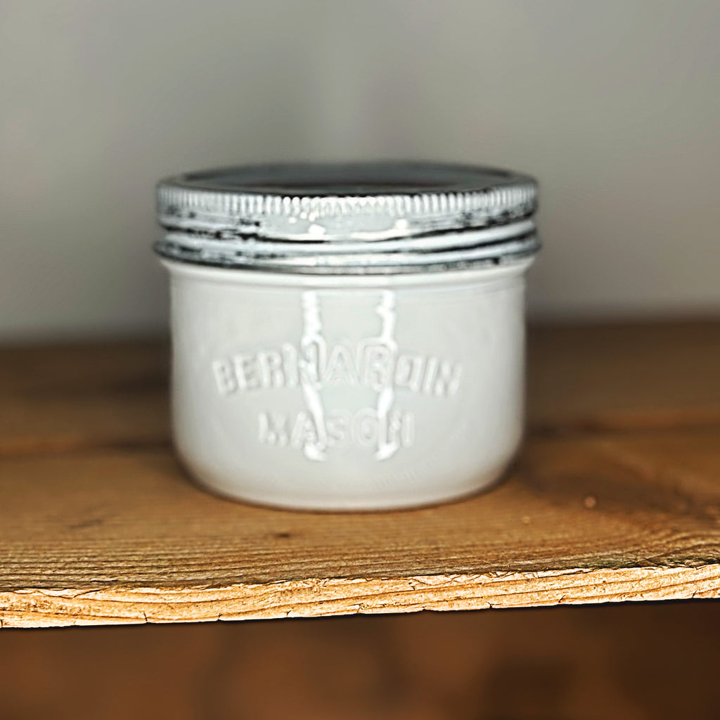 White mason jar with a metal lid on a wooden surface.