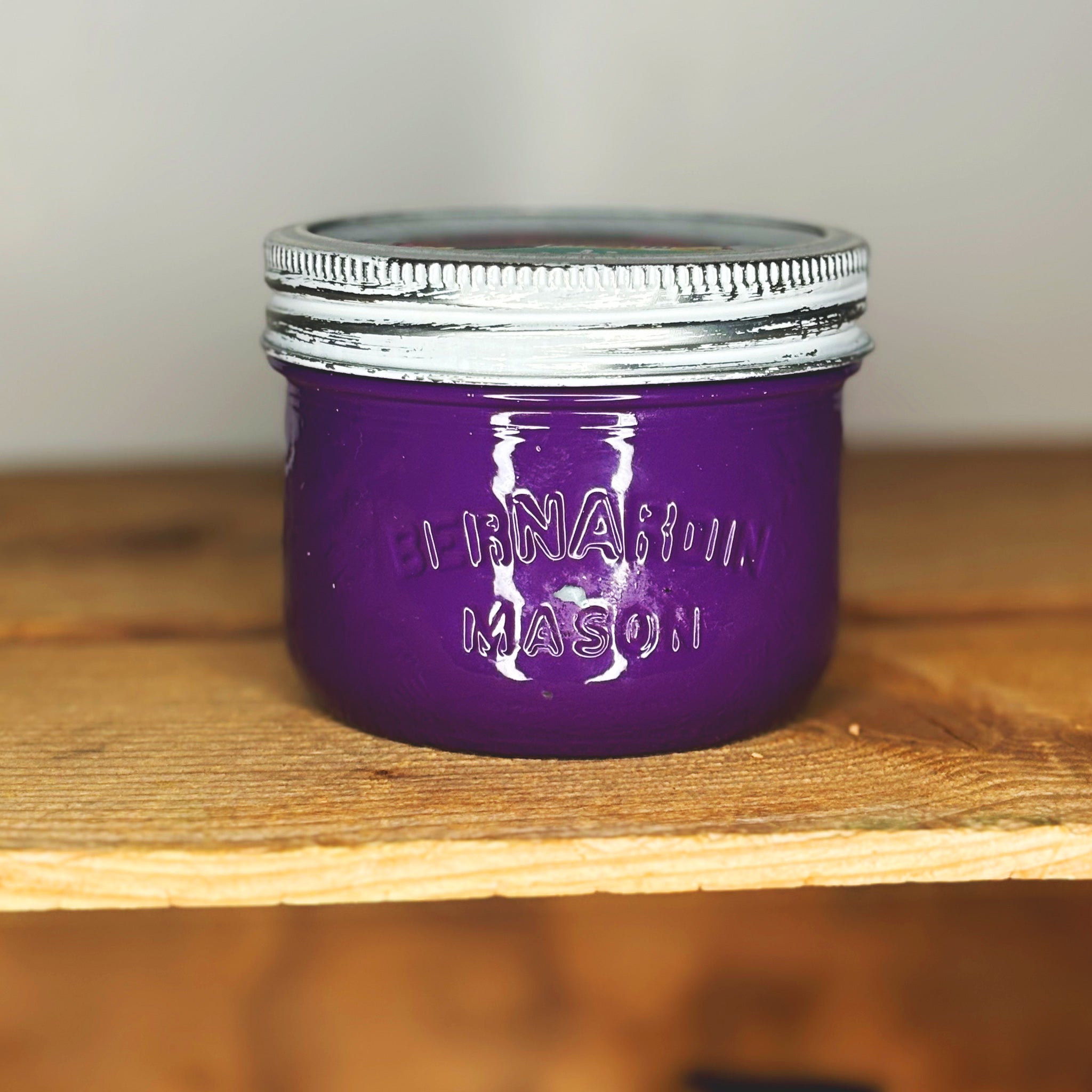 Purple mason jar with silver lid on a wooden surface.