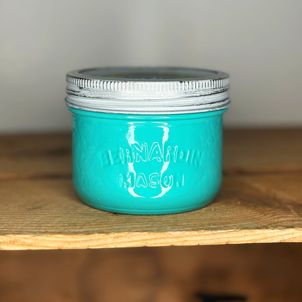 Turquoise mason jar with silver lid on a wooden surface.