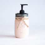 A pink mason jar soap dispenser with a pump on a white background.