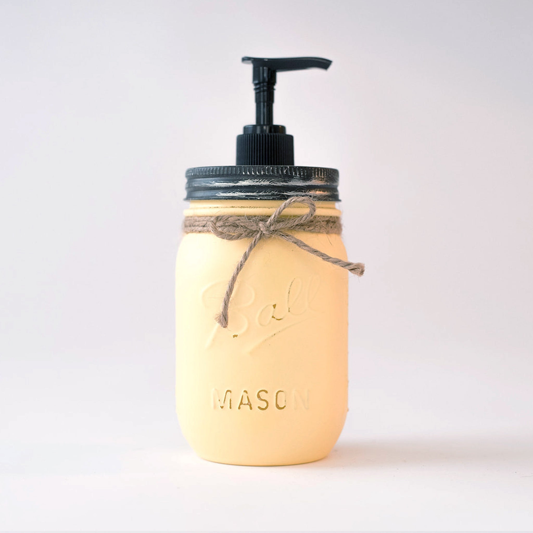 A yellow mason jar soap dispenser with pump on a white background.