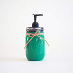 A green mason jar soap dispenser with a pump on a white background.