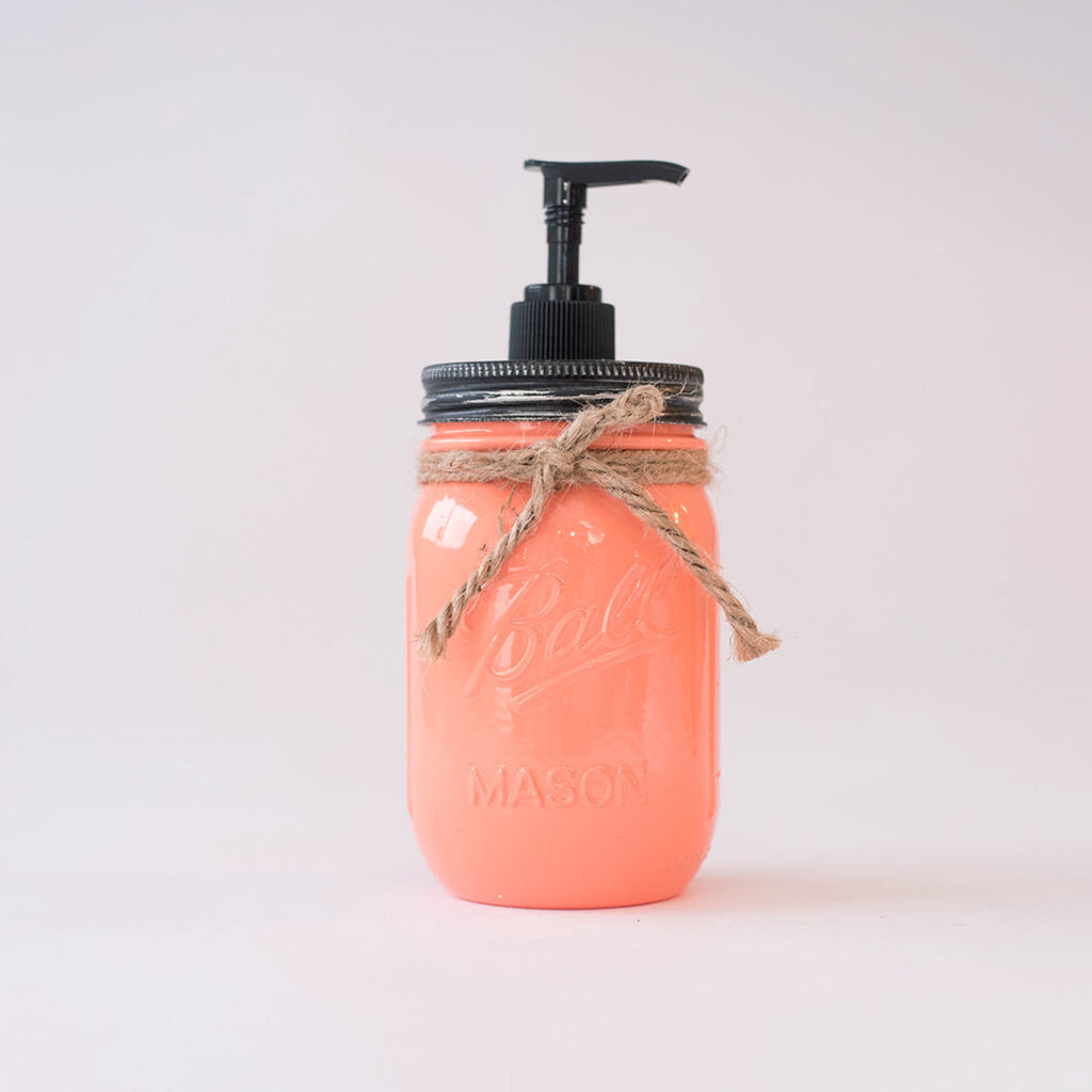 A coral-colored mason jar soap dispenser with a black pump on a white background.