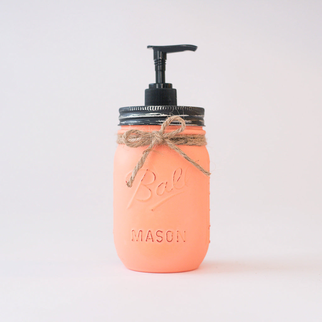 A coral-colored mason jar soap dispenser with a black pump on a white background.