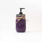 A purple mason jar soap dispenser with a pump and twine on a white background.