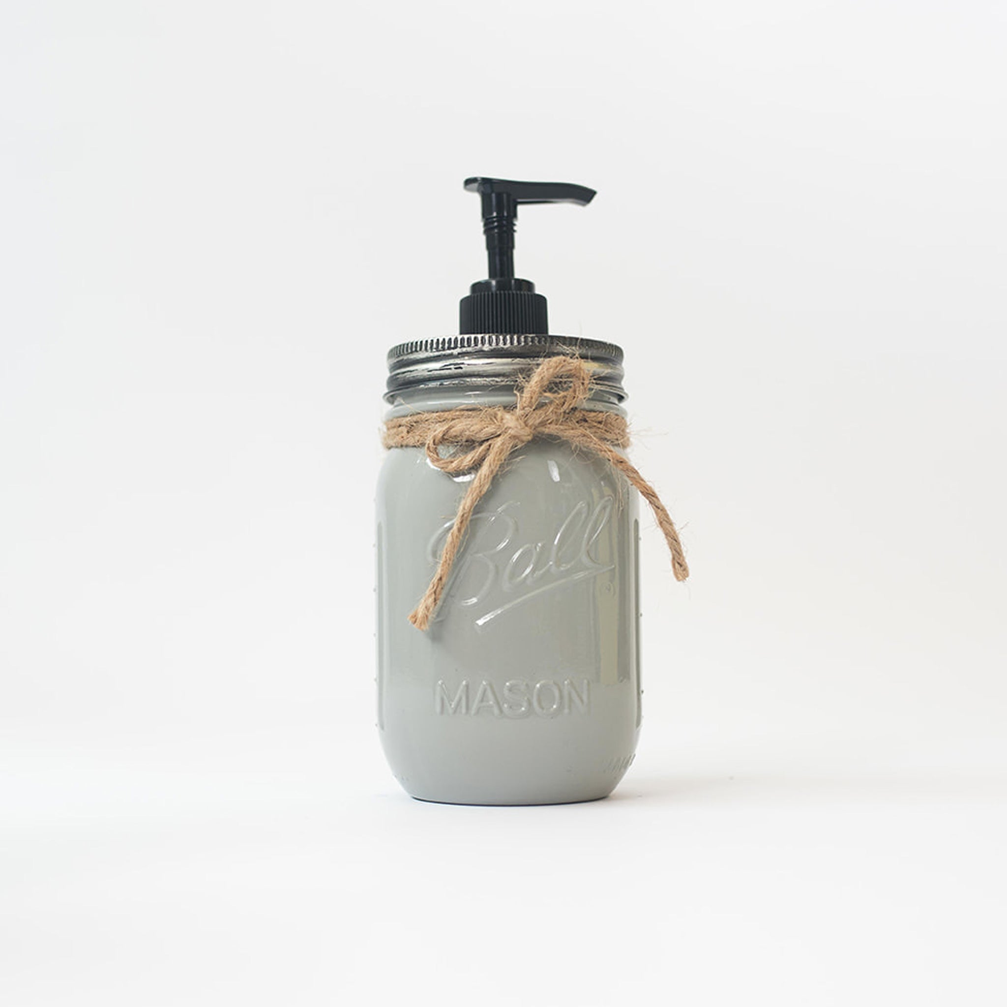 A grey mason jar soap dispenser with a pump and twine on a white background.