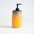 A yellow mason jar soap dispenser with a black pump on a white background.