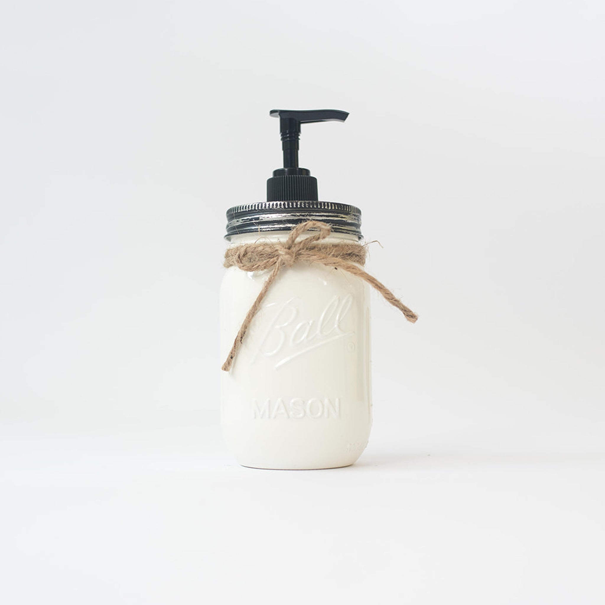 A mason jar soap dispenser with pump and twine on a white background.