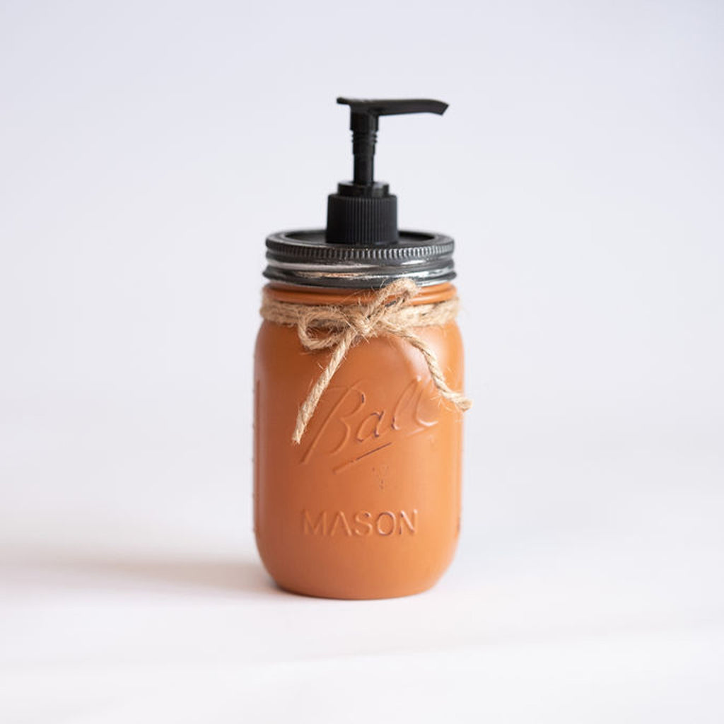 A brown mason jar soap dispenser with a pump on a light background.