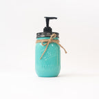 A turquoise mason jar soap dispenser with a pump and twine on a white background.