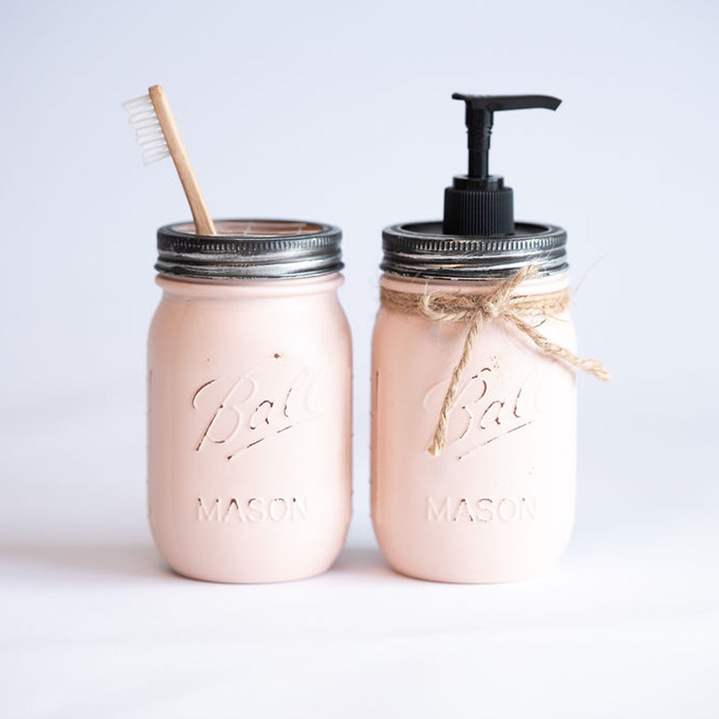 Two pink mason jars with a straw and pump on a light gray background.