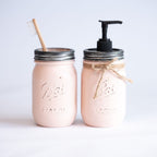 Two pink mason jars with a straw and pump on a light gray background.