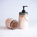 Mason jar soap dispenser with pump and decorative bow on a light background.