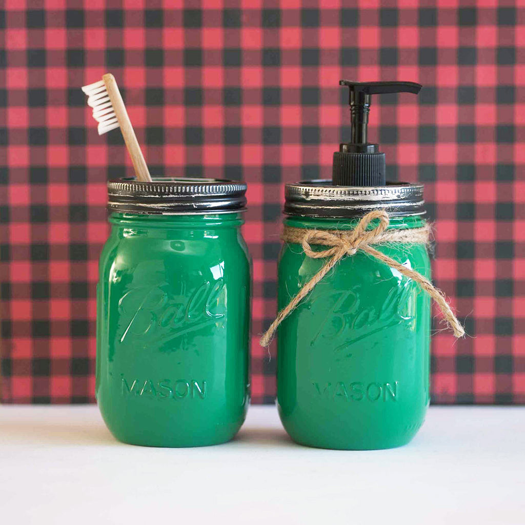 Two green mason jars with a toothbrush and pump dispenser against a red and black checkered background.