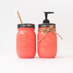 Two coral-colored mason jars with a straw and pump dispenser on a white background.