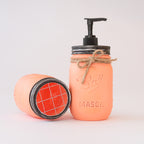 Coral-colored mason jar soap dispenser with pump on a white background.