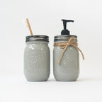 Two gray mason jars with a brush and pump dispenser on a white background.