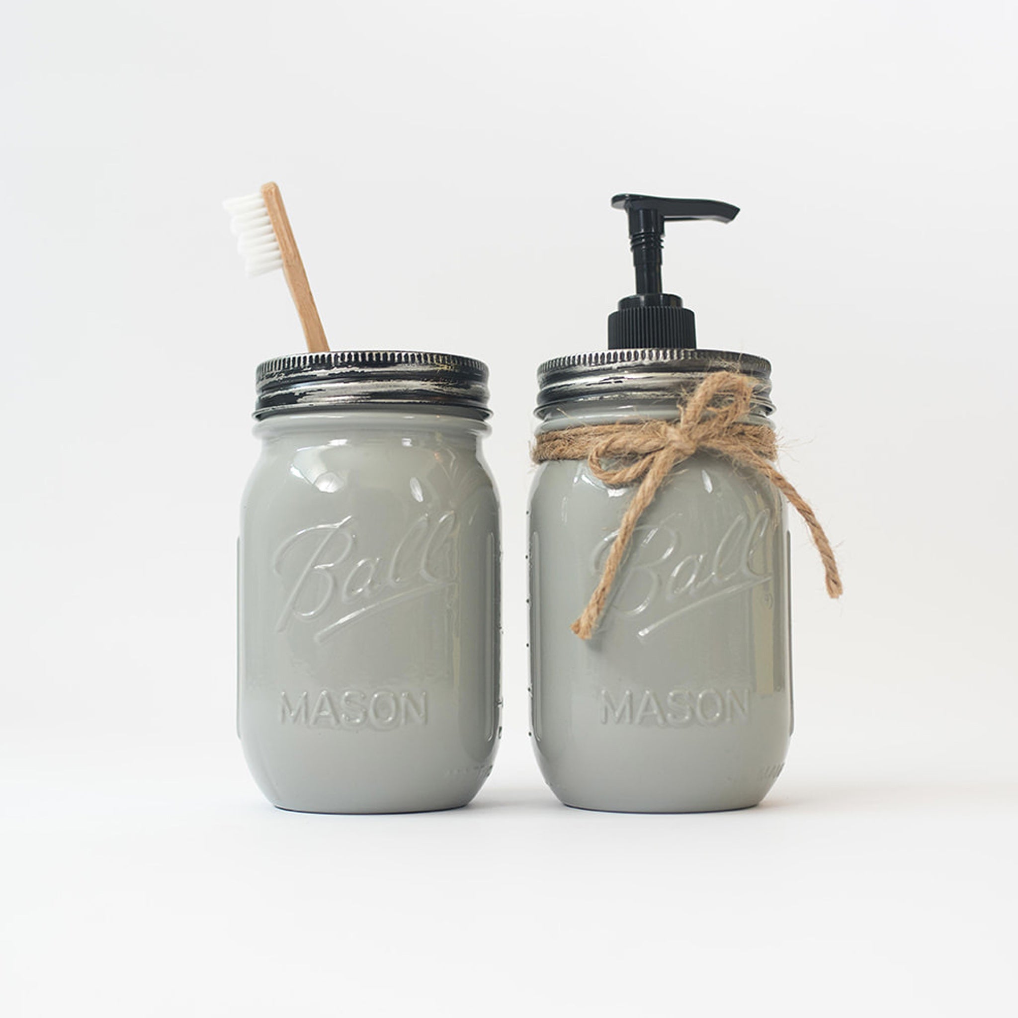 Two gray mason jars with a brush and pump dispenser on a white background.