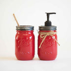 Two red mason jars, one with a toothbrush and the other with a pump dispenser on a white background.