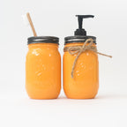 Two orange mason jars with a wooden toothbrush and pump dispenser on a white background.