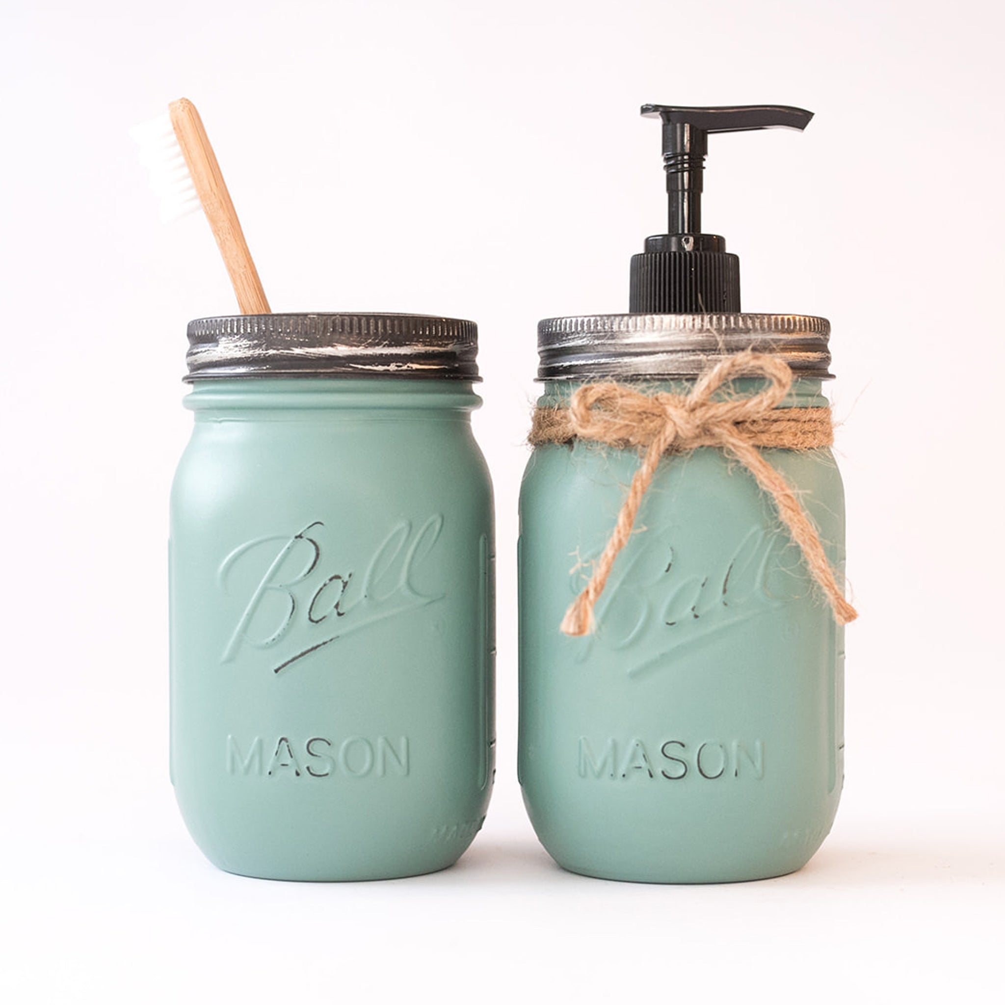 Two light blue mason jars with a straw and pump dispenser on a white background.