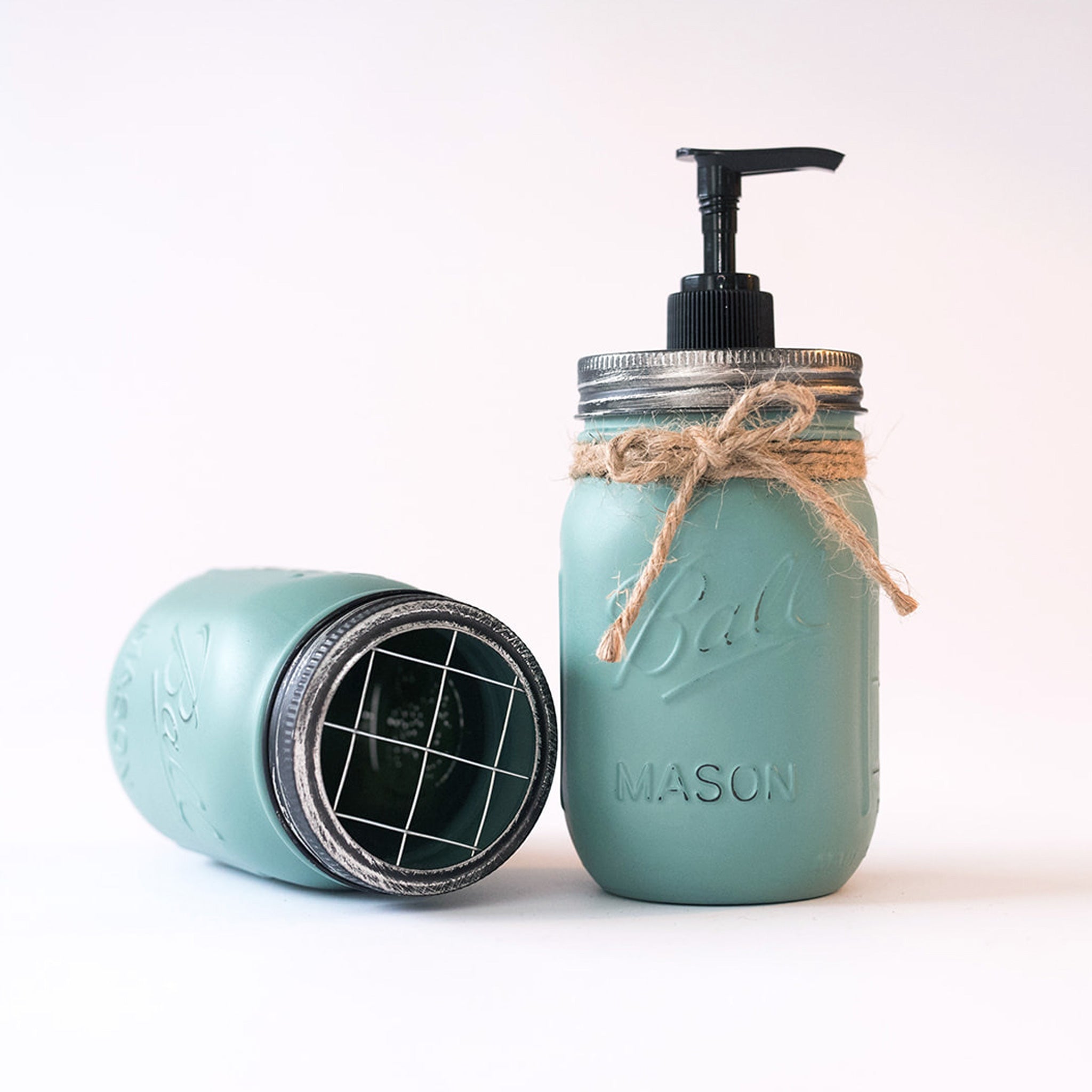 Mason jar soap dispenser with pump and twine on a white background.