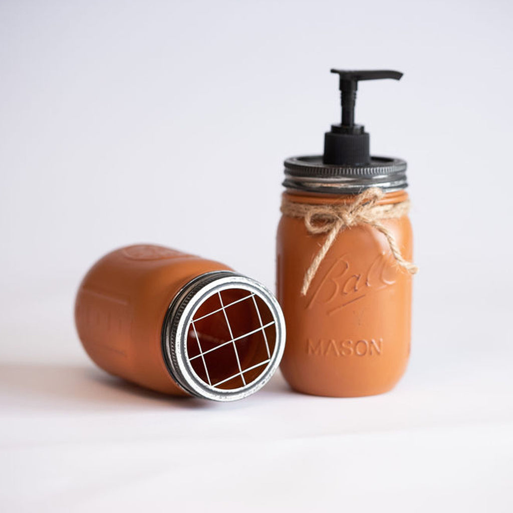Ceramic soap dispenser with pump and decorative bow on a light background.