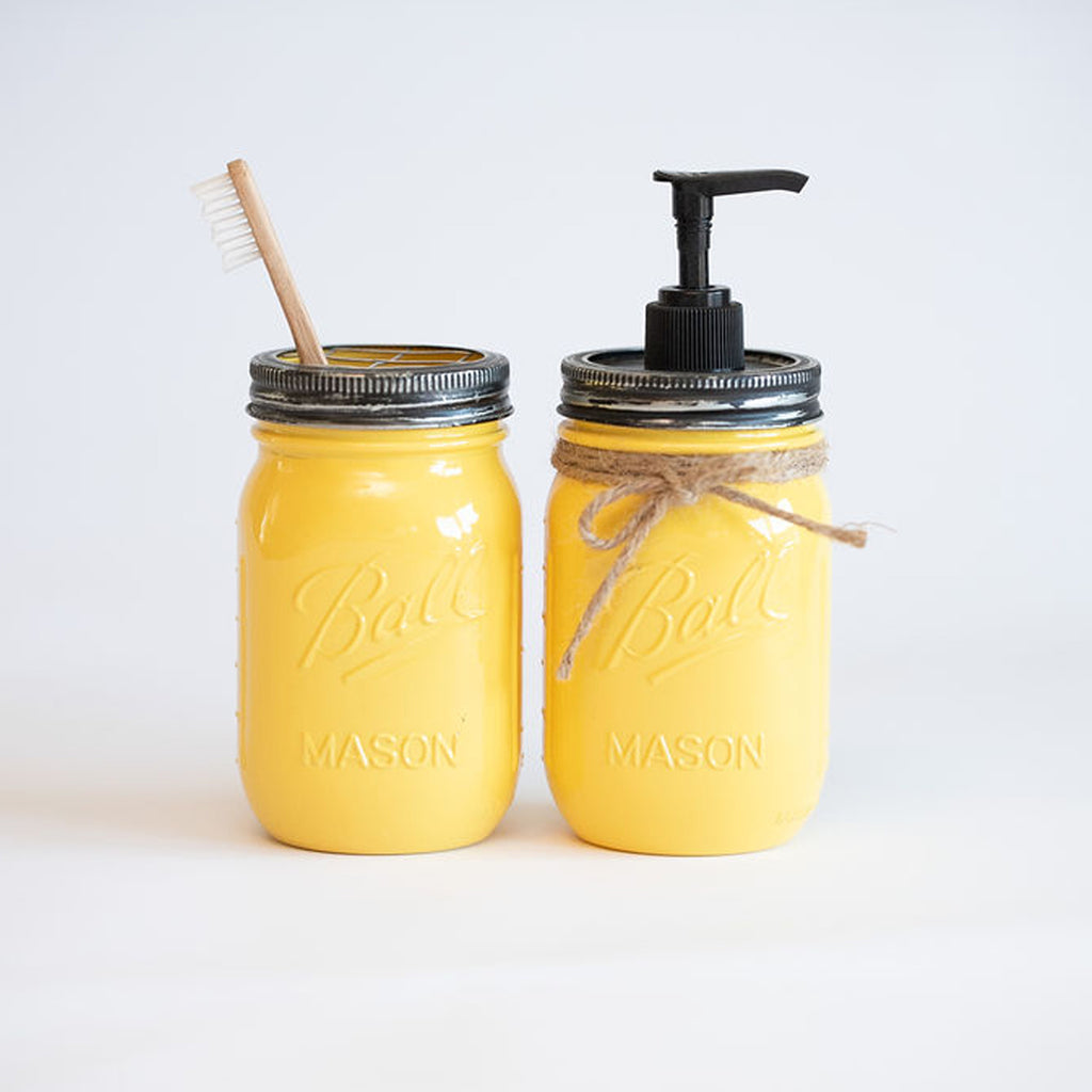 Two yellow mason jars with a straw and pump on a white background.