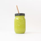 Lime green mason jar with a toothbrush in it on a white background.